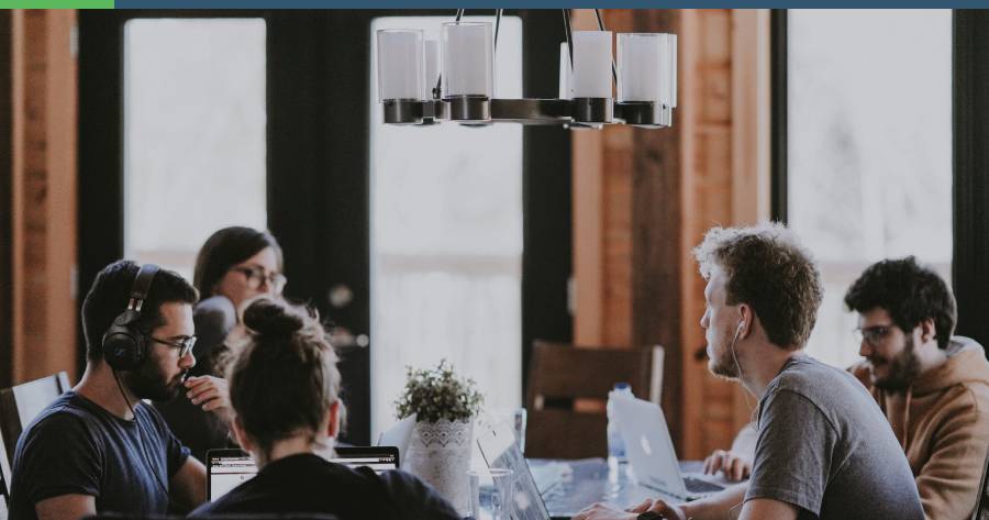 Five people sitting around a desk discussing an issue. Some are zoned out in work.