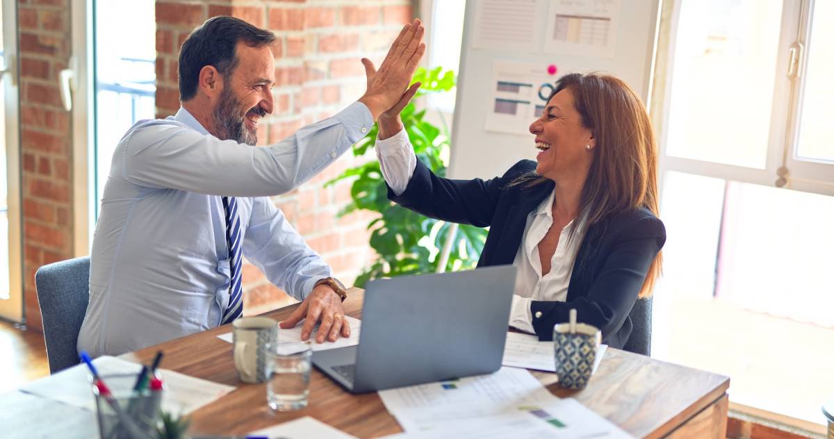 Two people in an office hi-5ing.