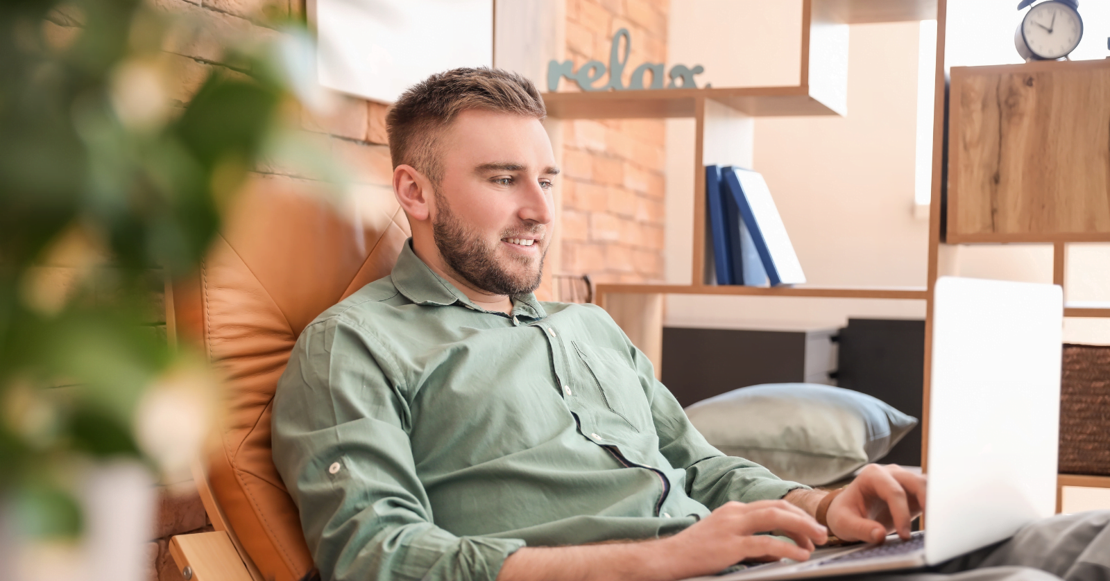 A person relaxing on his sofa and using a laptop.
