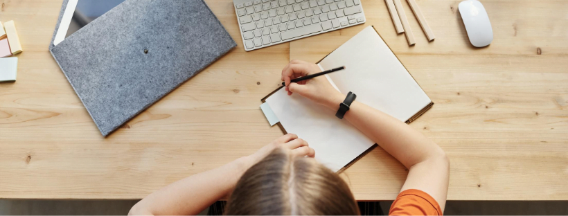 A woman writing in her diary. Her iPad and Apple gadgets are lying around.