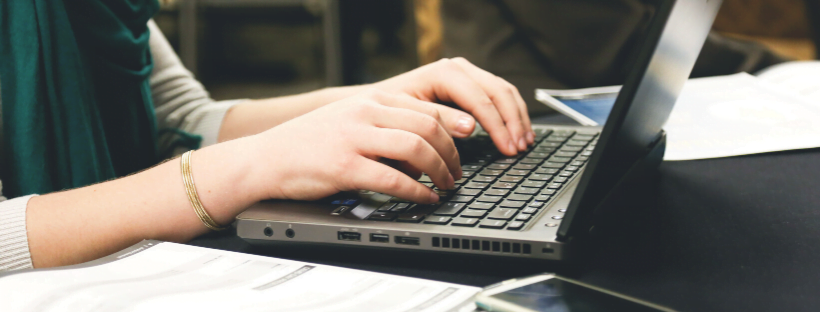Time-Consuming A woman wearing a green sweater/top typing on her laptop.