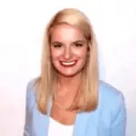 A photo of Madeleine Duprez smiling. She is wearing a professional attire with a white top and a blue coat.