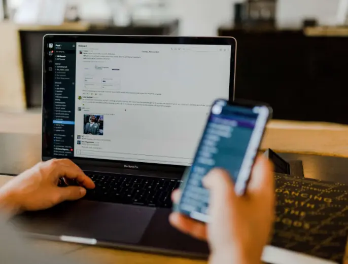 A person using Slack on his laptop and his phone.