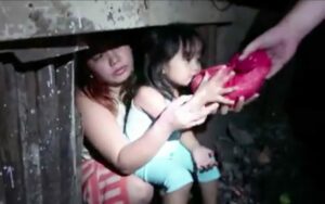 A child and her mother in the urban poor community being handed with food.