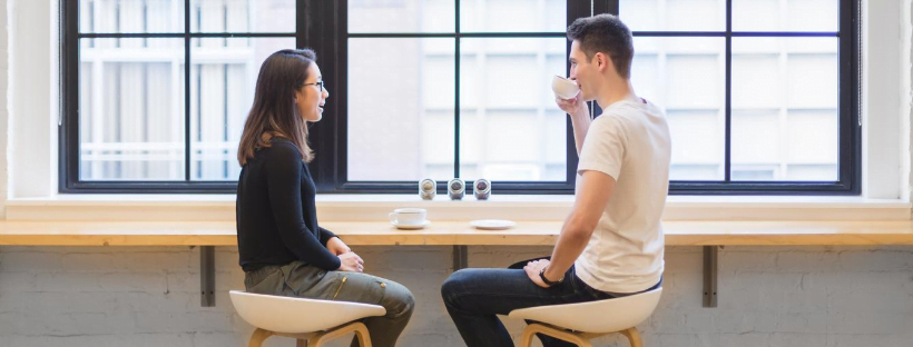 Two people drinking coffee, talking, and relaxing at a cafe.