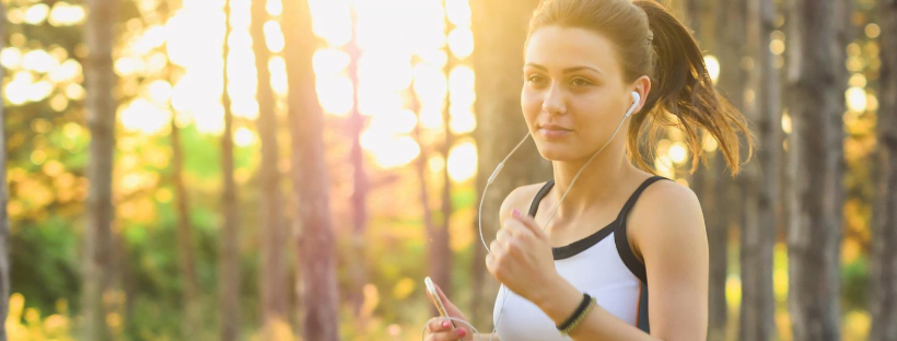 Exercise A woman listening to music while out for a jog in the forest/park.
