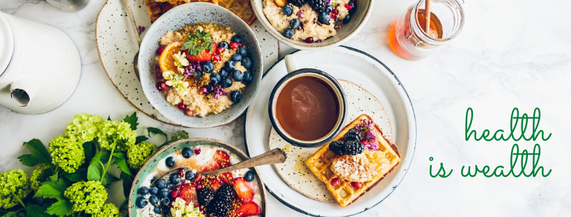 Health is wealth Several healthy foods arranged on a table. Decorative text reads: "Health is wealth."