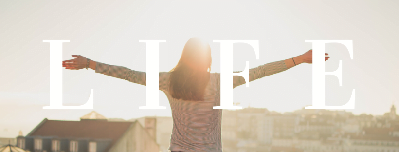 Live longer A lady looking over the city with both hands lifted high. The camera lens is blinded by the sunlight. Decorative text reads: "Life."