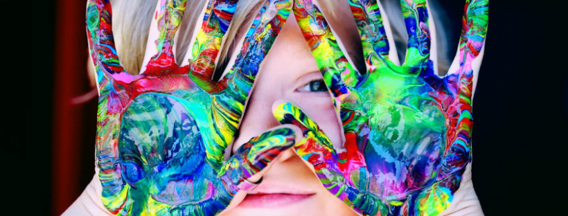 Kid with colorful paint on his hand.