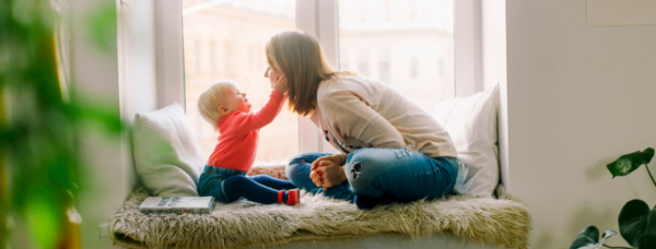 a woman and a child playing with a stuffed animal on a couch