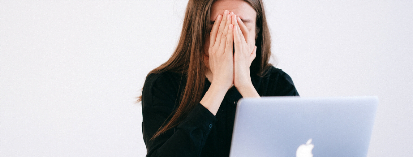 Stress A lady in front of a laptop, capping her hands over her face, as she feels stressed out.