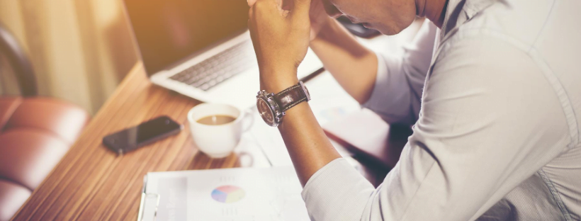 How Stress Affects Your Work A man looking at some graphs intensely. A laptop, his phone, and some coffee is kept nearby.